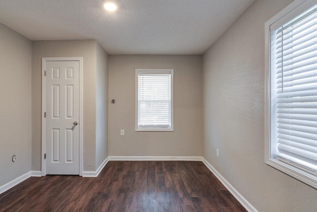 spare room featuring a textured ceiling and dark hardwood / wood-style floors