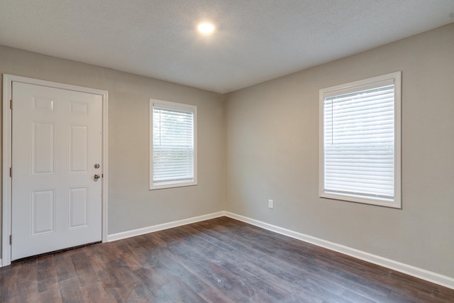 unfurnished room featuring dark wood-type flooring and a textured ceiling