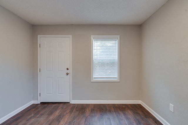 spare room featuring a textured ceiling and dark hardwood / wood-style floors