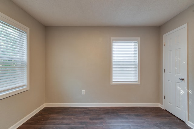 spare room featuring a textured ceiling and dark wood-type flooring