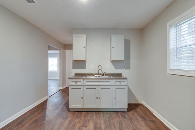 kitchen featuring dark hardwood / wood-style flooring, white cabinetry, sink, and plenty of natural light