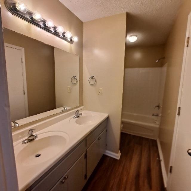 bathroom featuring vanity, hardwood / wood-style floors, a textured ceiling, and washtub / shower combination