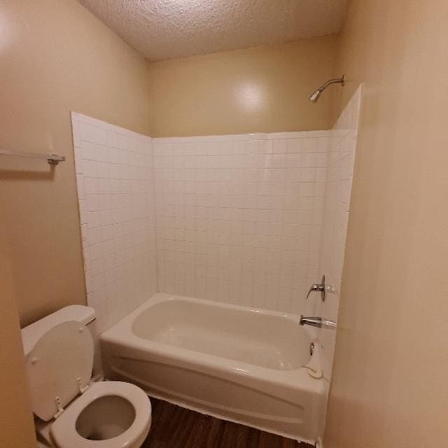 bathroom featuring a textured ceiling, toilet, and shower / bathtub combination