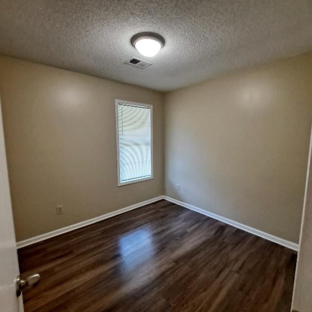 unfurnished room featuring a textured ceiling and dark hardwood / wood-style floors