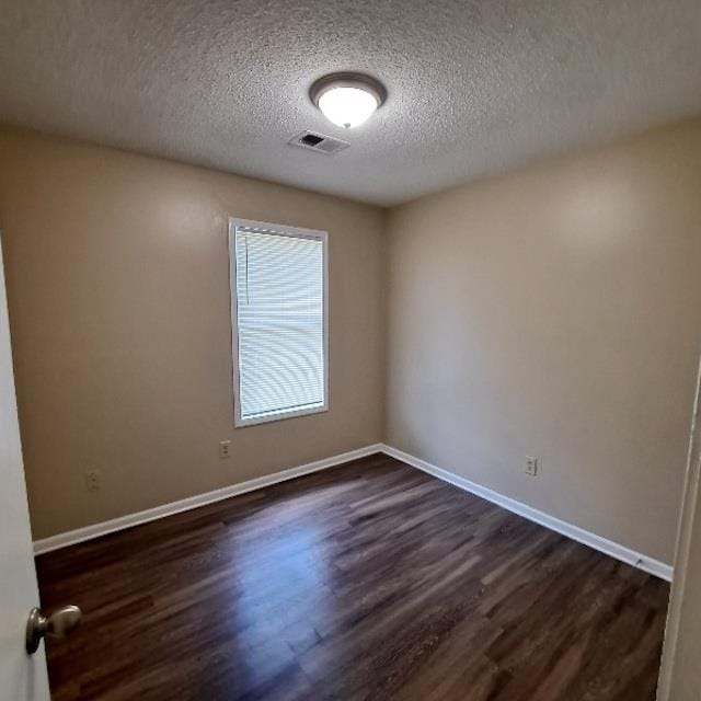 empty room featuring dark wood-type flooring and a textured ceiling