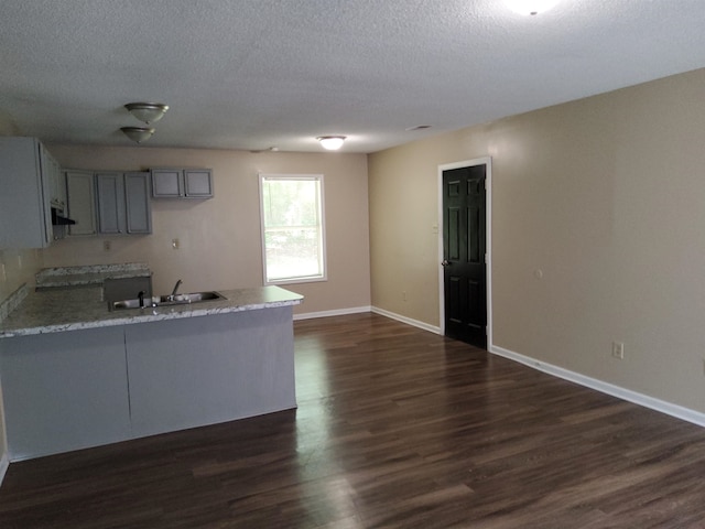 kitchen featuring kitchen peninsula, dark hardwood / wood-style flooring, a textured ceiling, sink, and gray cabinets