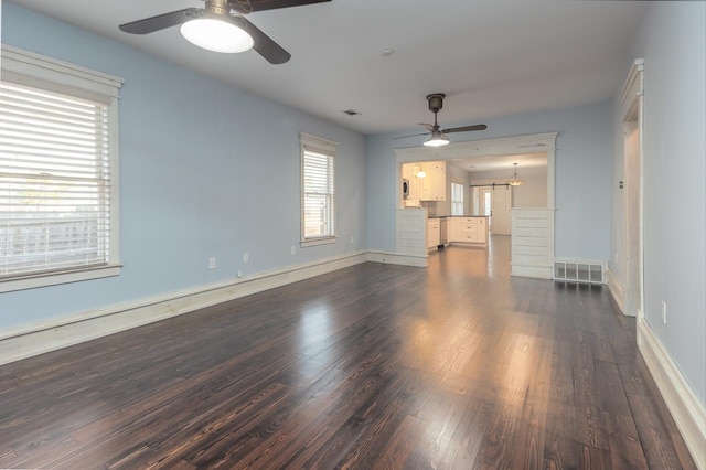 unfurnished living room with dark hardwood / wood-style floors and ceiling fan with notable chandelier