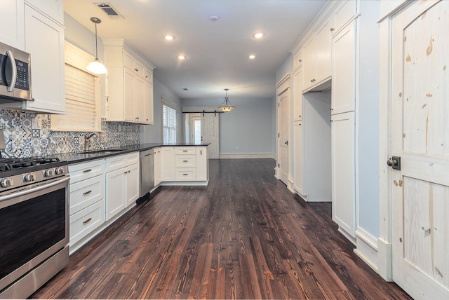 kitchen featuring stainless steel appliances, dark wood-type flooring, sink, a barn door, and decorative light fixtures