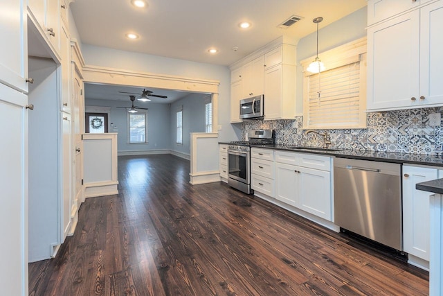 kitchen featuring white cabinets, stainless steel appliances, dark hardwood / wood-style floors, and hanging light fixtures