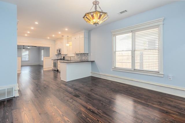 kitchen with decorative backsplash, appliances with stainless steel finishes, pendant lighting, dark hardwood / wood-style floors, and white cabinetry