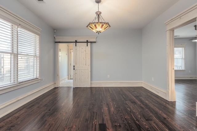 unfurnished room with dark hardwood / wood-style floors, a barn door, and ceiling fan