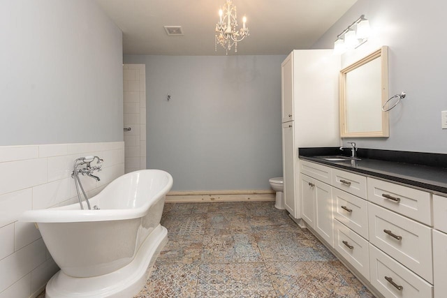 bathroom with a tub to relax in, vanity, tile walls, a chandelier, and toilet