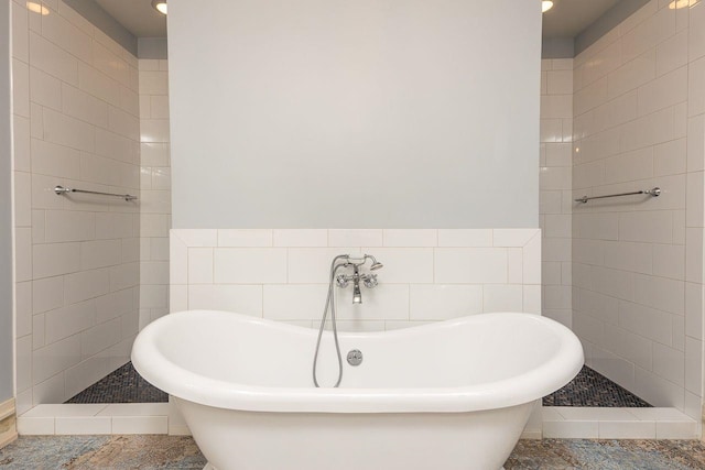 bathroom featuring a bath, tile patterned floors, and tile walls