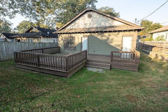 back of house with a lawn, an outdoor structure, and a wooden deck