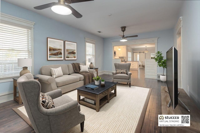 living room featuring ceiling fan with notable chandelier and hardwood / wood-style flooring