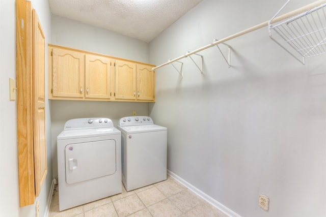 washroom with washer and clothes dryer, cabinets, and a textured ceiling