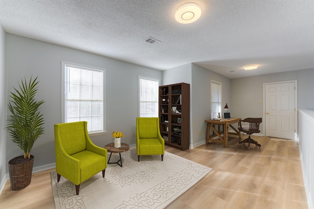 sitting room with light hardwood / wood-style floors and a textured ceiling