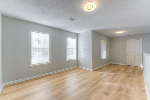 spare room featuring a textured ceiling and light hardwood / wood-style flooring