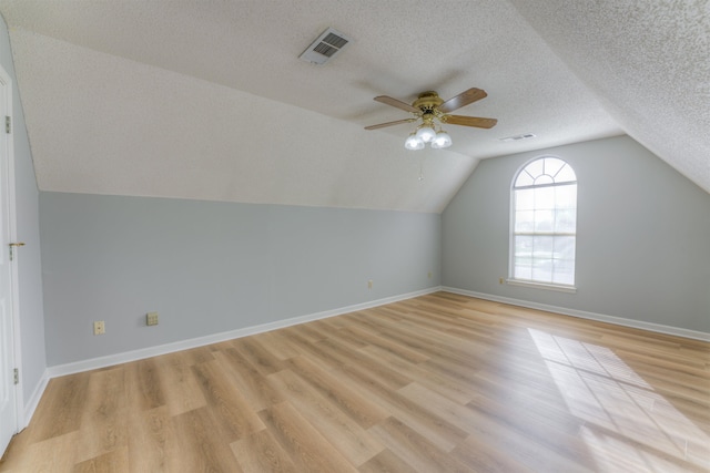 additional living space featuring a textured ceiling, light hardwood / wood-style floors, ceiling fan, and lofted ceiling