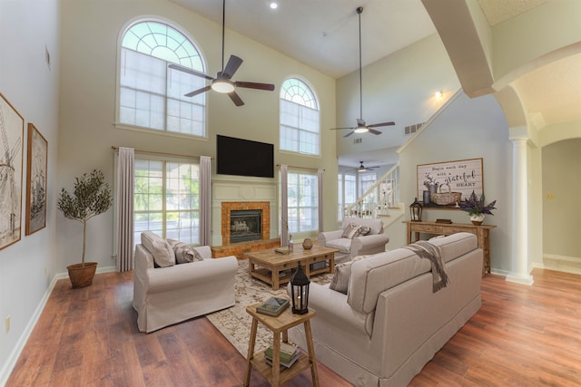 living room featuring wood-type flooring, high vaulted ceiling, a healthy amount of sunlight, and ornate columns