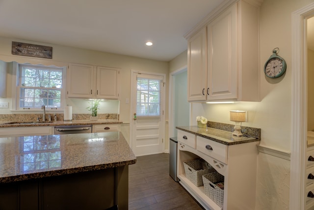 kitchen with sink, stainless steel dishwasher, dark stone countertops, dark hardwood / wood-style flooring, and white cabinetry