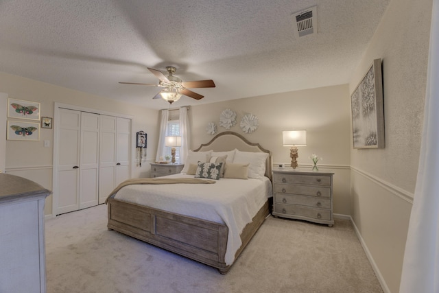 bedroom with light carpet, a textured ceiling, a closet, and ceiling fan