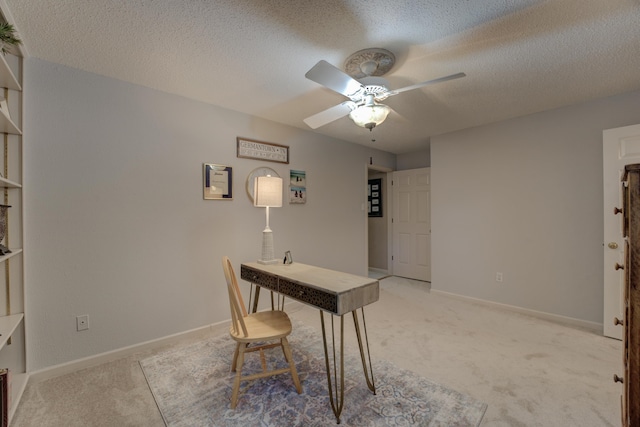 unfurnished office featuring light carpet, ceiling fan, and a textured ceiling