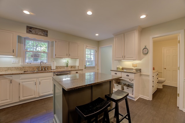 kitchen with white cabinets, dark hardwood / wood-style floors, a center island, and sink