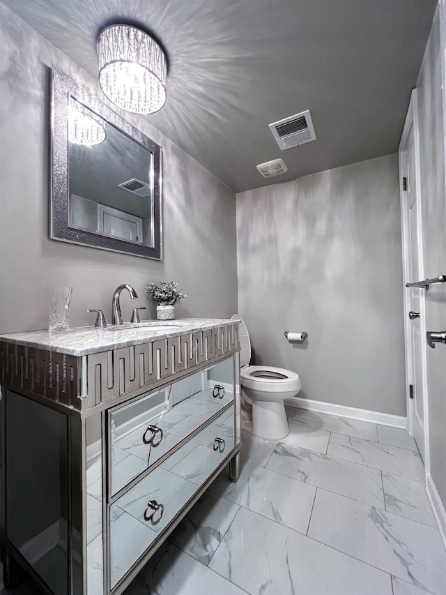 bathroom featuring vanity, toilet, and a notable chandelier