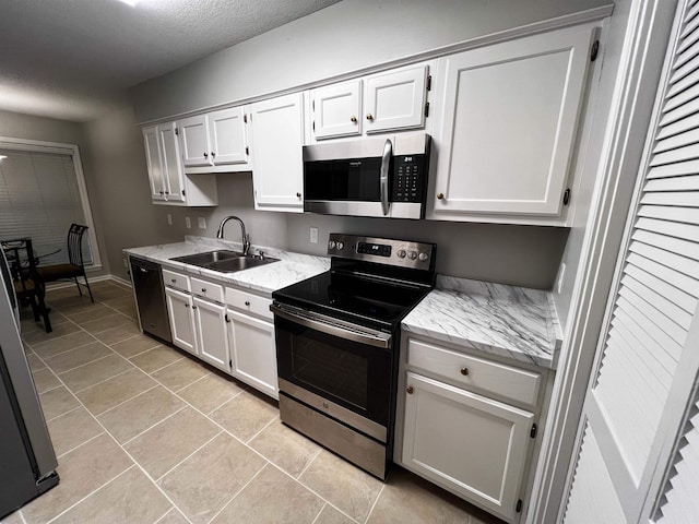 kitchen featuring white cabinets, sink, light tile patterned floors, a textured ceiling, and appliances with stainless steel finishes