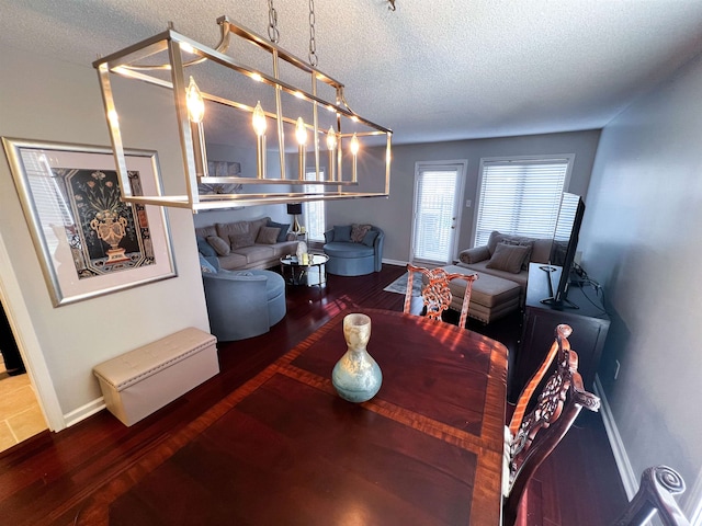 dining space with dark wood-type flooring and a textured ceiling