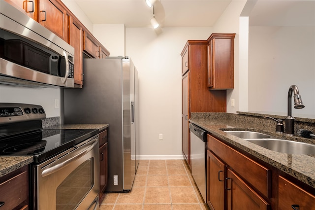 kitchen with sink, rail lighting, dark stone countertops, and appliances with stainless steel finishes