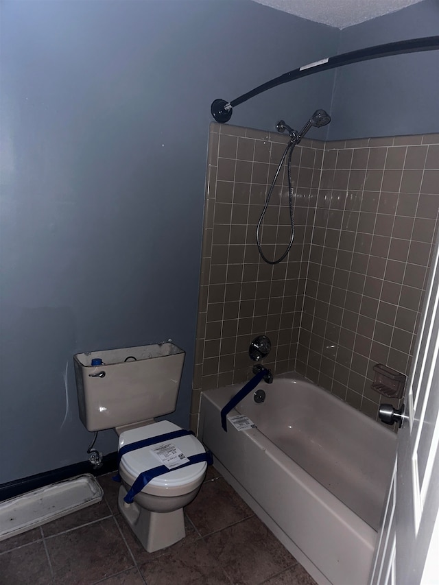 bathroom featuring tile patterned flooring, tiled shower / bath, a textured ceiling, and toilet