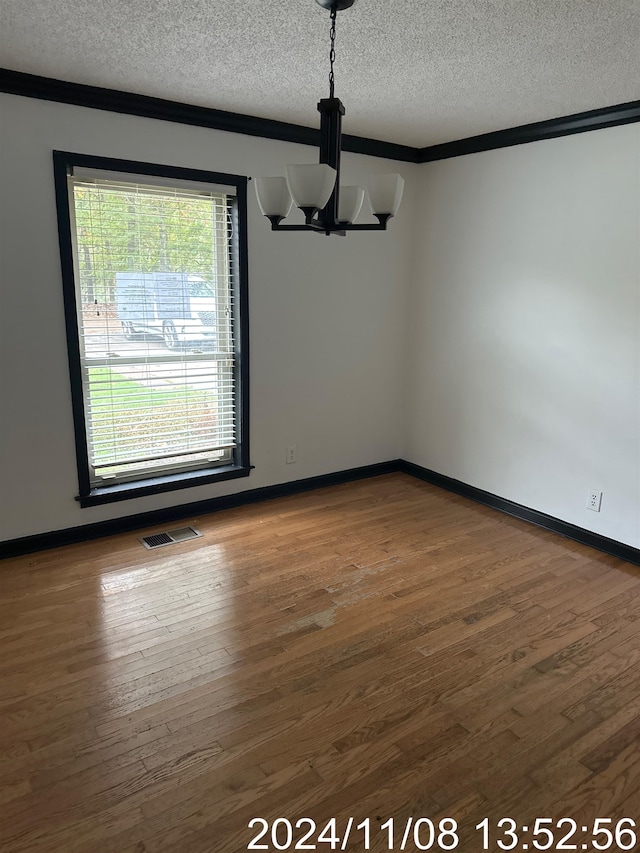 unfurnished dining area featuring a chandelier, hardwood / wood-style floors, a textured ceiling, and crown molding