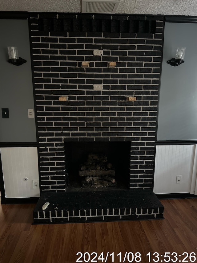 room details with wood-type flooring, a textured ceiling, and a brick fireplace