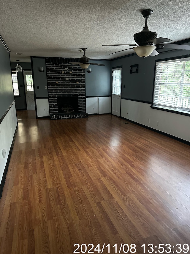 unfurnished living room featuring ceiling fan, hardwood / wood-style floors, and a textured ceiling