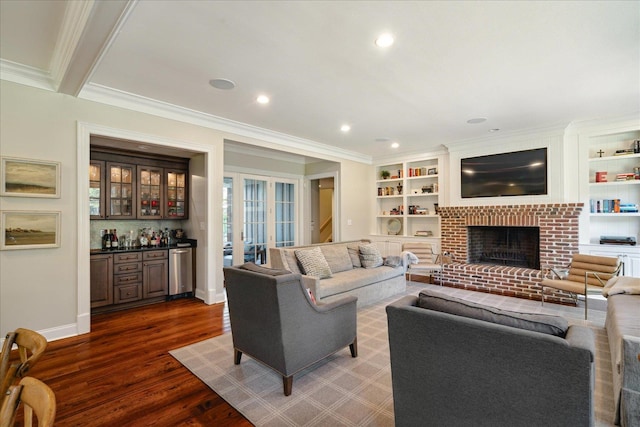 living room featuring ornamental molding, dark wood-type flooring, beam ceiling, a fireplace, and bar area