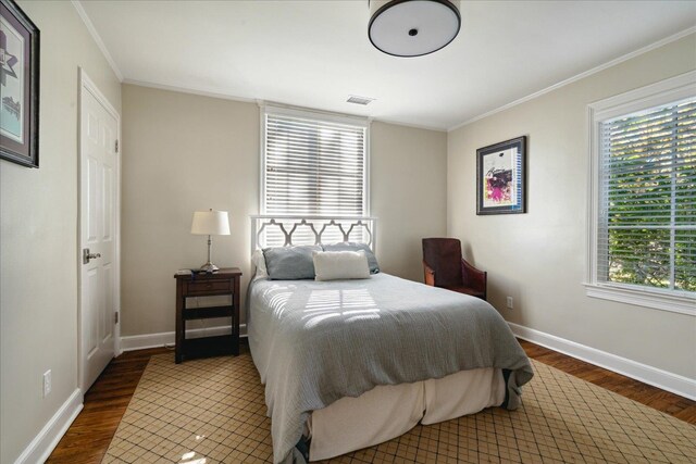 bedroom with ornamental molding and dark wood-type flooring