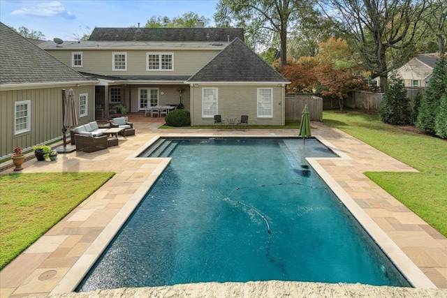 rear view of house featuring outdoor lounge area, a yard, a fenced in pool, and a patio area