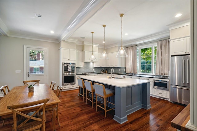 kitchen with a center island with sink, white cabinets, sink, dark hardwood / wood-style floors, and appliances with stainless steel finishes