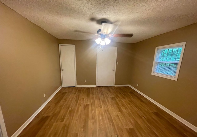 unfurnished bedroom with hardwood / wood-style floors, a textured ceiling, and ceiling fan