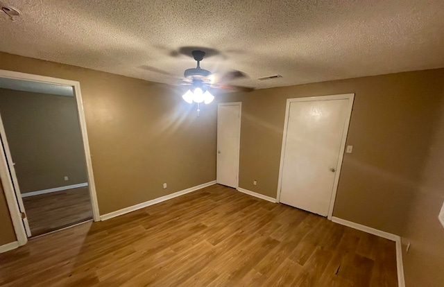 empty room featuring ceiling fan, hardwood / wood-style floors, and a textured ceiling