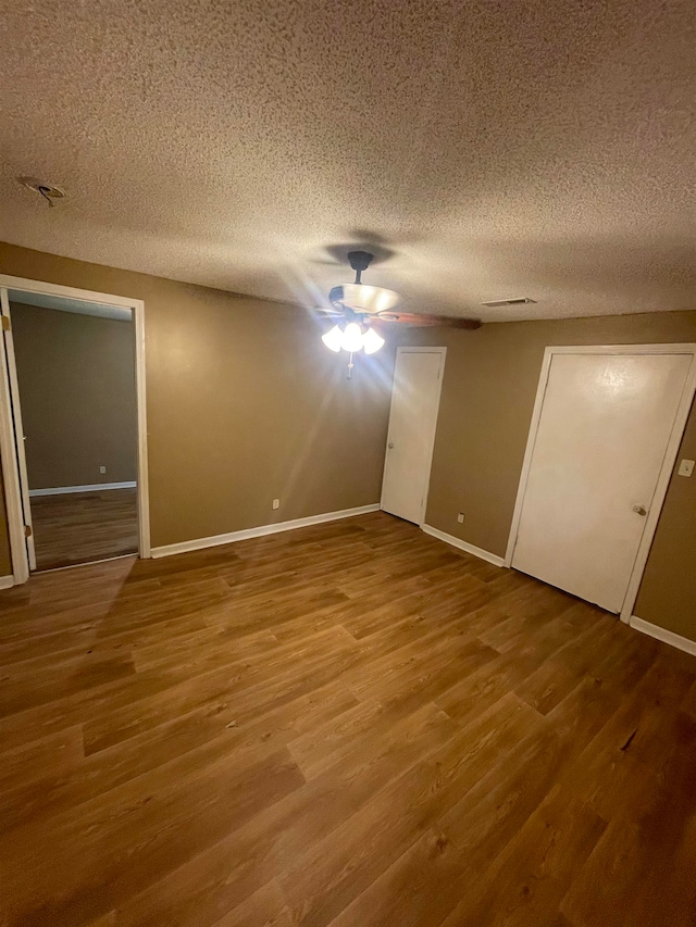 unfurnished bedroom with wood-type flooring, a textured ceiling, a closet, and ceiling fan