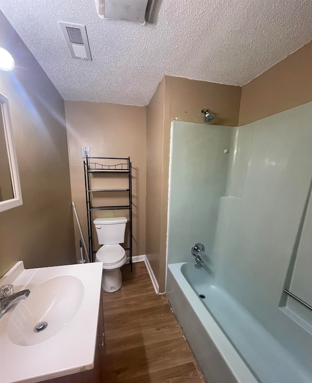 full bathroom with vanity, a textured ceiling, shower / washtub combination, wood-type flooring, and toilet