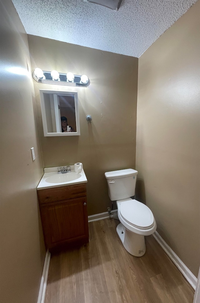 bathroom with a textured ceiling, vanity, hardwood / wood-style flooring, and toilet