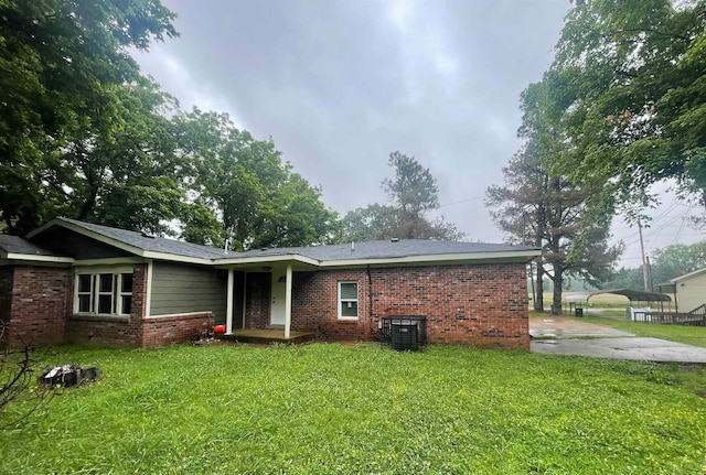 back of property with a carport, cooling unit, and a lawn