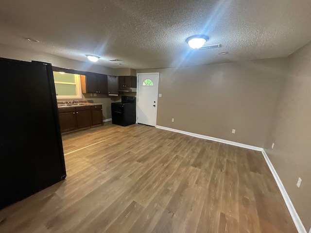 kitchen featuring black appliances, a textured ceiling, and light wood-type flooring