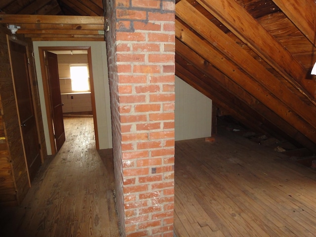 hallway with hardwood / wood-style floors and vaulted ceiling