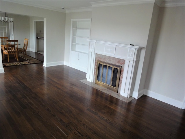 unfurnished living room featuring a chandelier, dark hardwood / wood-style flooring, built in features, and ornamental molding