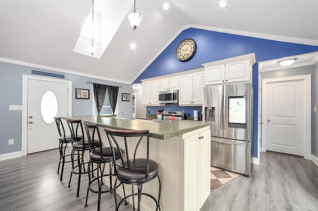 kitchen with vaulted ceiling with skylight, a center island, ornamental molding, and appliances with stainless steel finishes